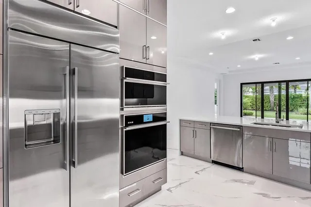 a kitchen with stainless steel appliances kitchen island granite countertop a refrigerator and a sink