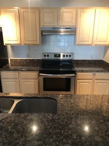 a kitchen with granite countertop a stove a sink and a granite counter tops