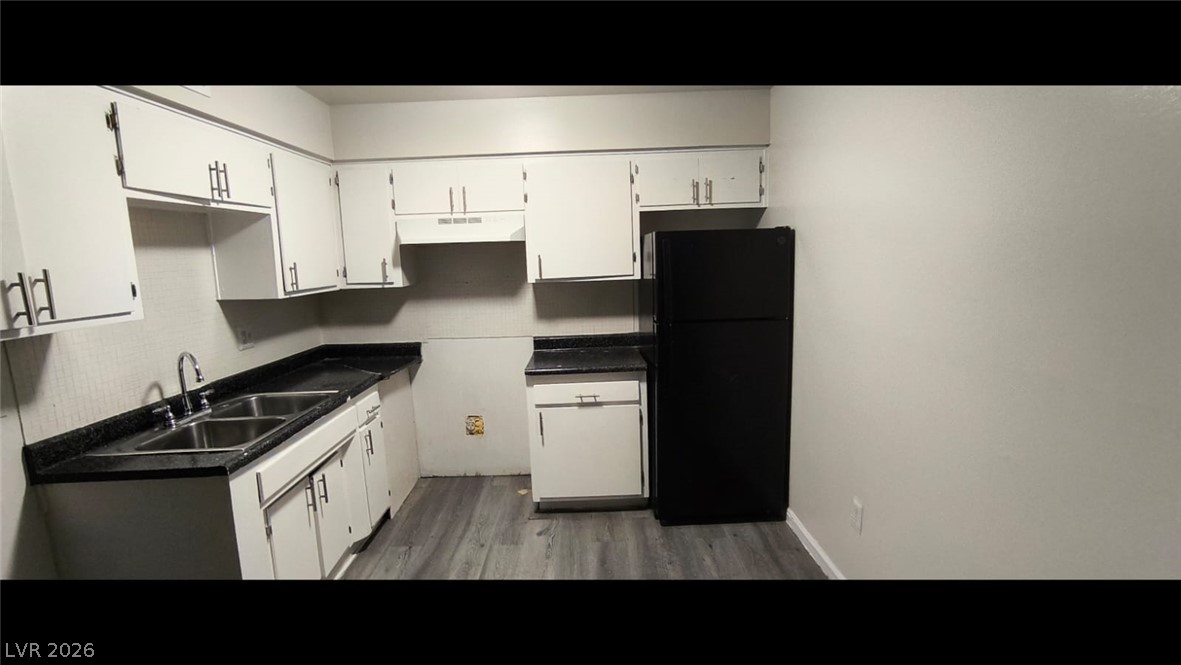 1075 East Desert Inn Road, Unit 5 Las Vegas, NV 89109 - Photo 4 of 12 A compact kitchen featuring dark countertops and modern gray flooring.