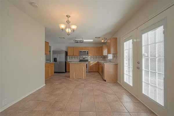 a view of a kitchen with kitchen island stainless steel appliances refrigerator sink and cabinets