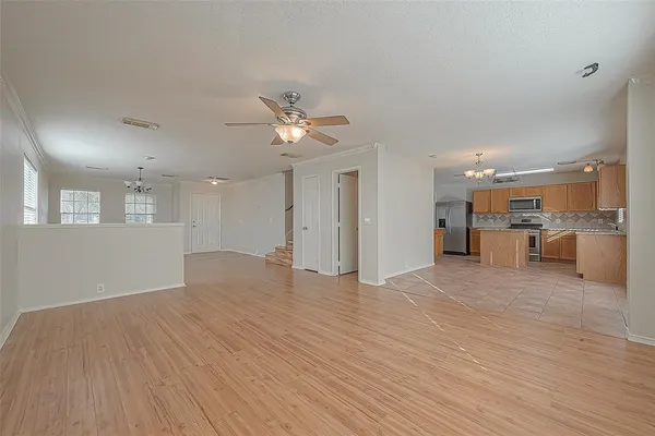 a view of an empty room with wooden floor and a kitchen