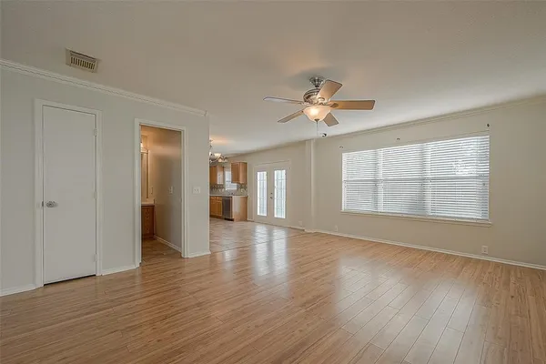 an empty room with wooden floor chandelier and windows