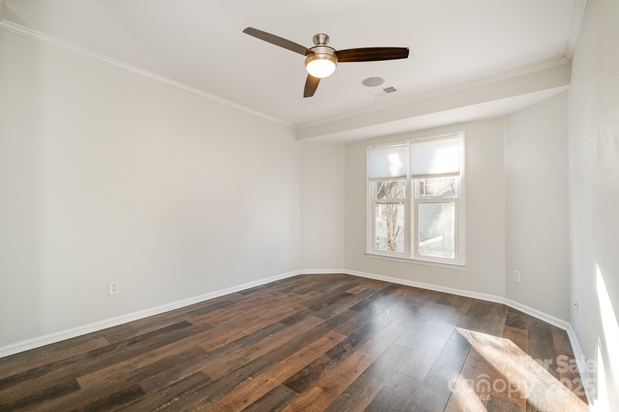 433 West 8th Street Charlotte, NC 28202 - Photo 17 of 25 an empty room with wooden floor ceiling fan and windows