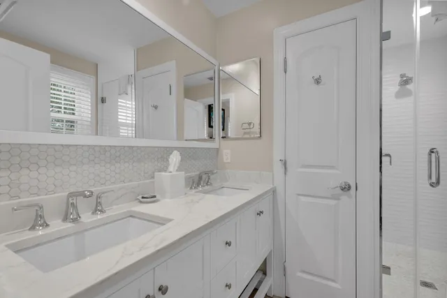a bathroom with double vanity sink a mirror and shower