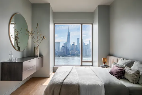 a bedroom with a bed a mirror and a large window