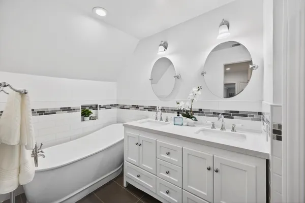 a bathroom with a toilet a double vanity sink and a mirror