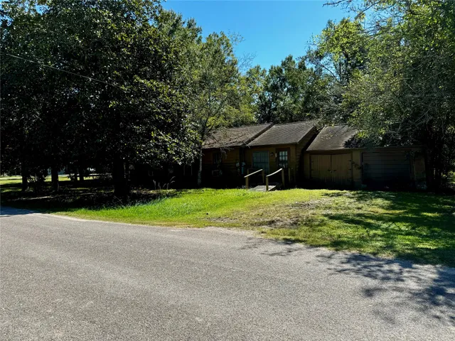 a brick house with a big yard and large trees