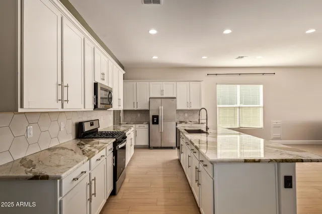 a kitchen with stainless steel appliances granite countertop a stove a sink and a refrigerator