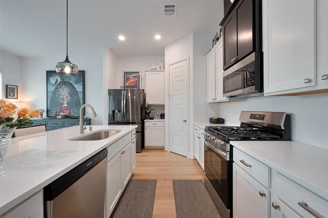 a large kitchen with stainless steel appliances granite countertop a sink a stove and a refrigerator