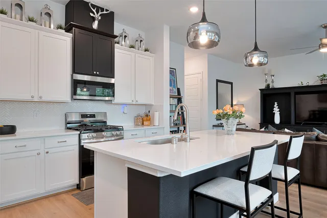a kitchen with stainless steel appliances a table chairs and white cabinets