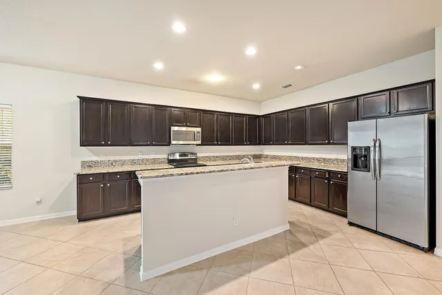 a kitchen with stainless steel appliances granite countertop a refrigerator sink and stove