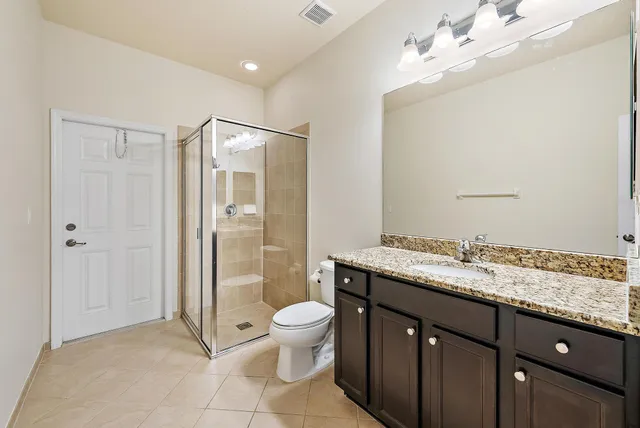 a bathroom with a granite countertop sink a toilet a mirror and shower