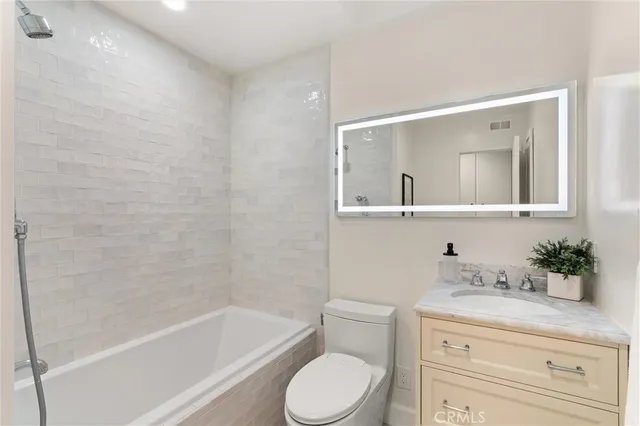 a bathroom with a granite countertop sink a toilet and bathtub