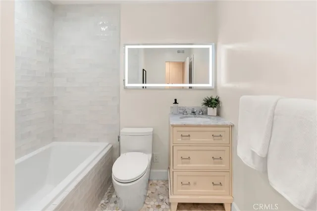 a bathroom with a granite countertop toilet sink and mirror