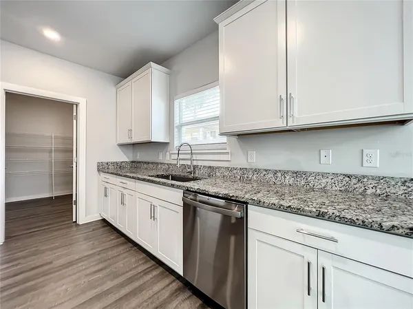 a kitchen with granite countertop white cabinets and a sink