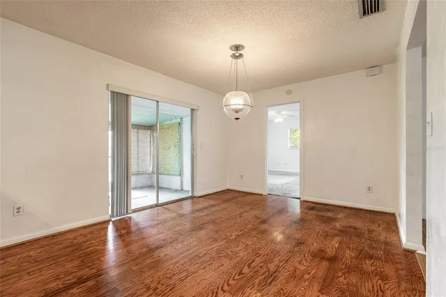an empty room with wooden floor mirror and windows