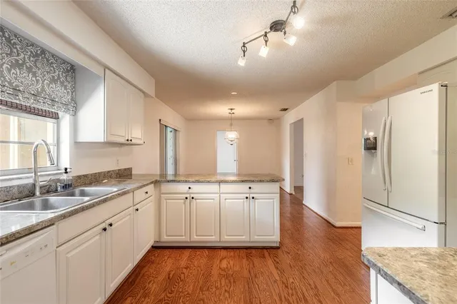 a large kitchen with a wooden floor and white stainless steel appliances