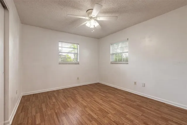an empty room with wooden floor and windows