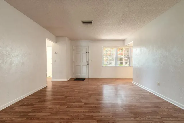 a view of an empty room with window and wooden floor