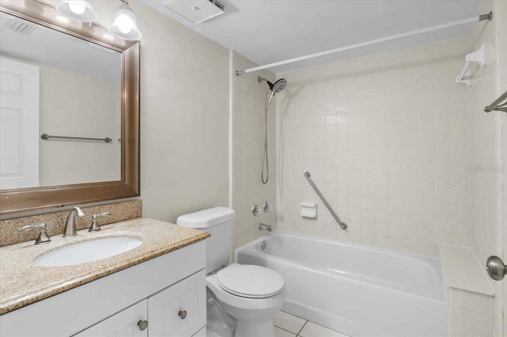 1127 Pine Ridge Circle West, Unit A2 Tarpon Springs, FL 34688 - Photo 12 of 18 a bathroom with a granite countertop sink a toilet and a bathtub