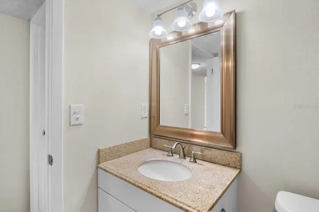 a bathroom with a granite countertop sink and a mirror