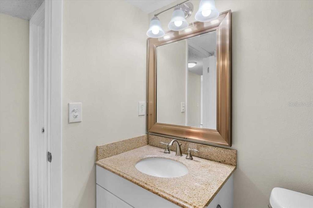 1127 Pine Ridge Circle West, Unit A2 Tarpon Springs, FL 34688 - Photo 13 of 18 a bathroom with a granite countertop sink and a mirror
