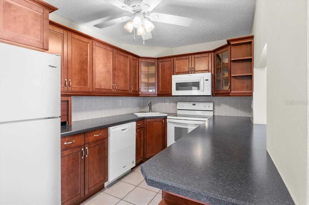 1127 Pine Ridge Circle West, Unit A2 Tarpon Springs, FL 34688 - Photo 6 of 18 a kitchen with stainless steel appliances granite countertop a refrigerator a sink dishwasher a stove with wooden cabinets