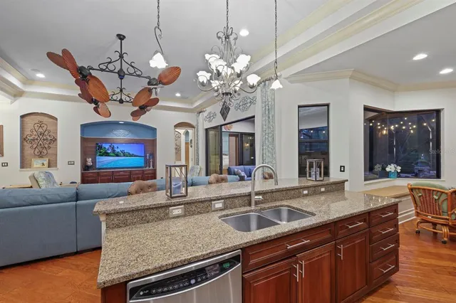 a living room with granite countertop furniture a chandelier and kitchen view