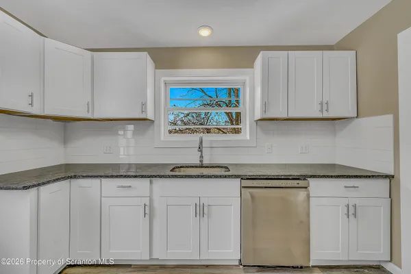 a kitchen with granite countertop white cabinets and a sink