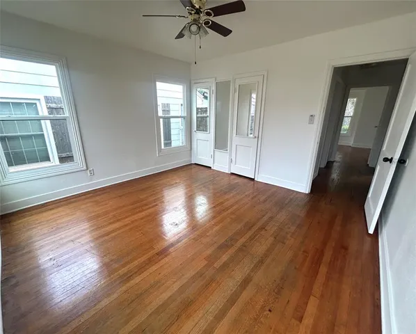 a view of an empty room with wooden floor and a window