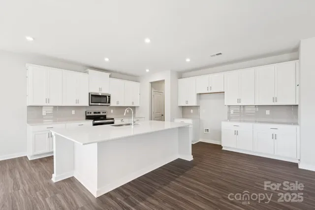 a kitchen with stainless steel appliances a refrigerator sink and white cabinets