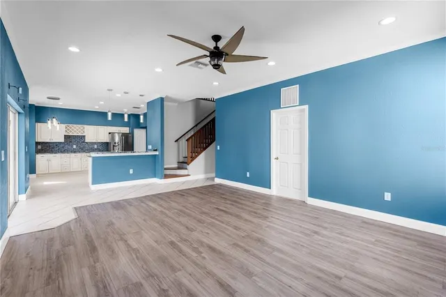a view of an empty room with a window and kitchen view