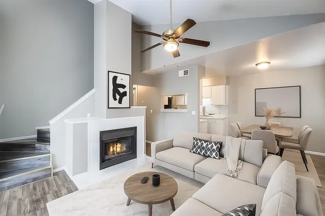 a living room with furniture a fireplace and a ceiling fan