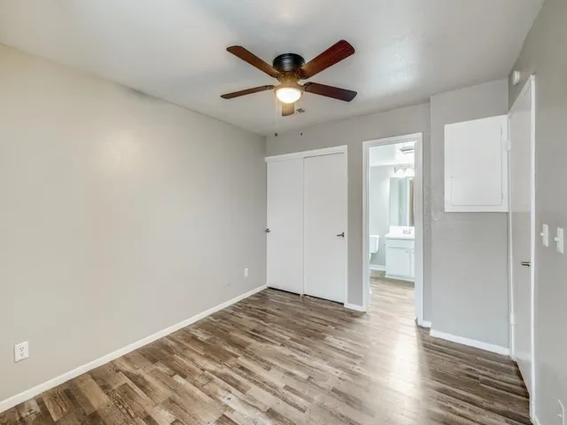 a view of empty room with wooden floor and ceiling fan