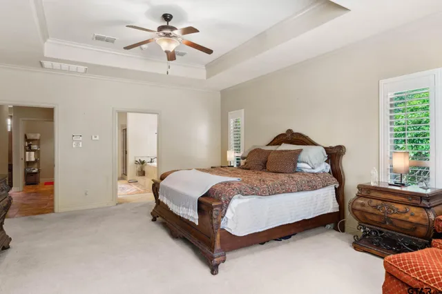 a spacious bedroom with a bed and a chandelier fan