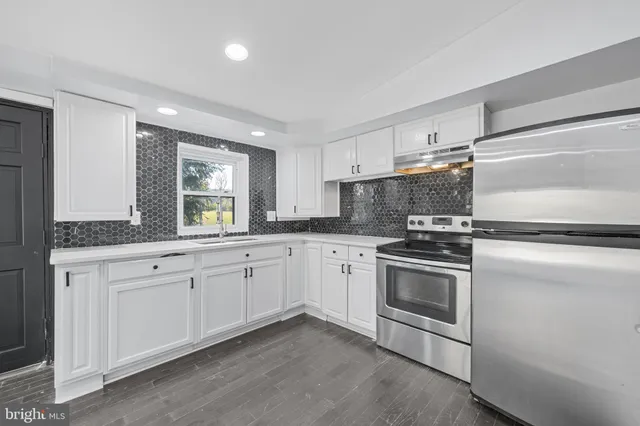 a kitchen with granite countertop white cabinets and stainless steel appliances