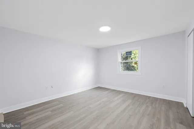 a view of an empty room with wooden floor and closet