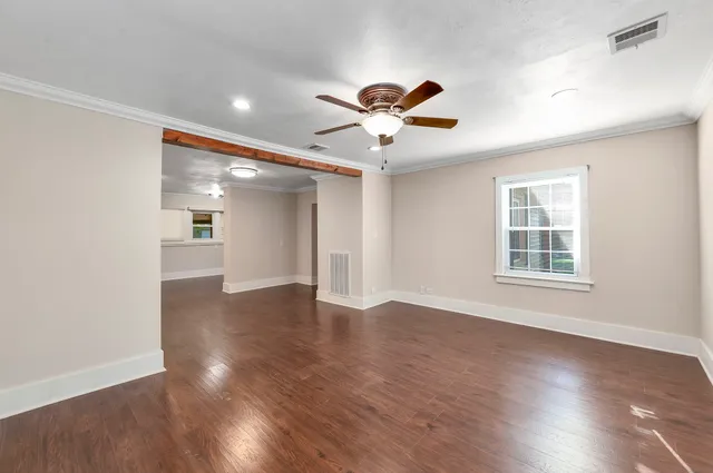 a view of empty room with wooden floor and fan