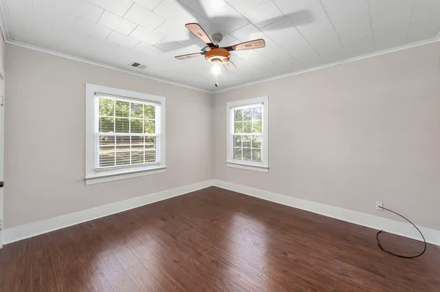 a view of an empty room with wooden floor and a window