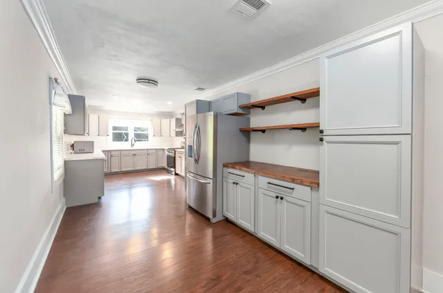 a kitchen with white cabinets and wooden floor