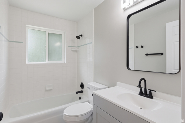 629 King Circle Layton, UT 84041 - Photo 11 of 26 Bathroom featuring a white bathtub, white tiled shower surround with accent band, and a frosted sliding window