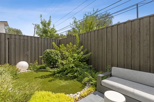 a backyard of a house with table and chairs plants and wooden fence