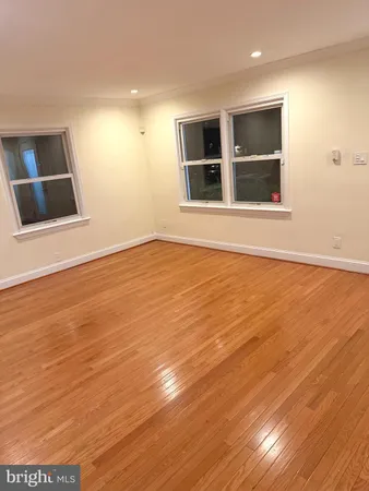 a view of empty room with wooden floor and window