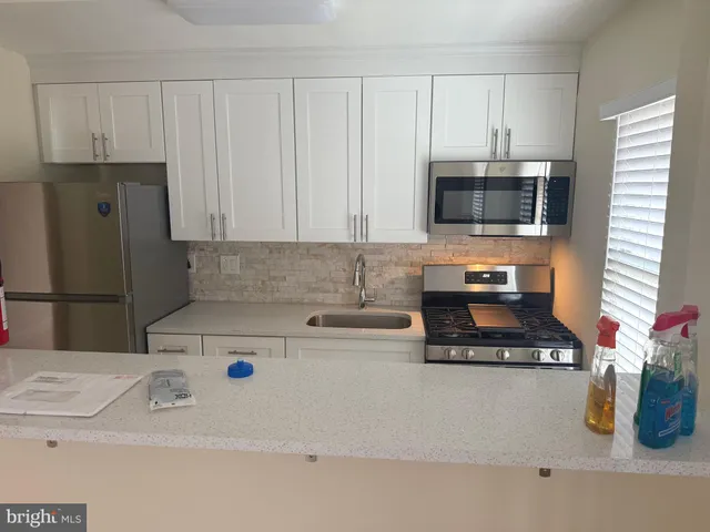 a kitchen with stainless steel appliances a stove a microwave a refrigerator a sink and cabinets