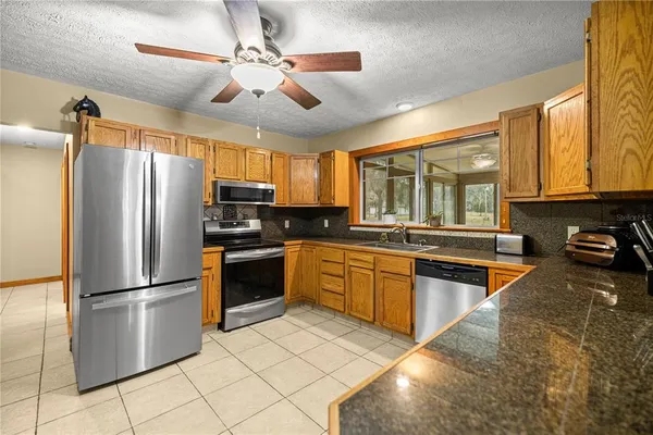 a kitchen with stainless steel appliances granite countertop a refrigerator a stove a sink a dining table and chairs with wooden floor