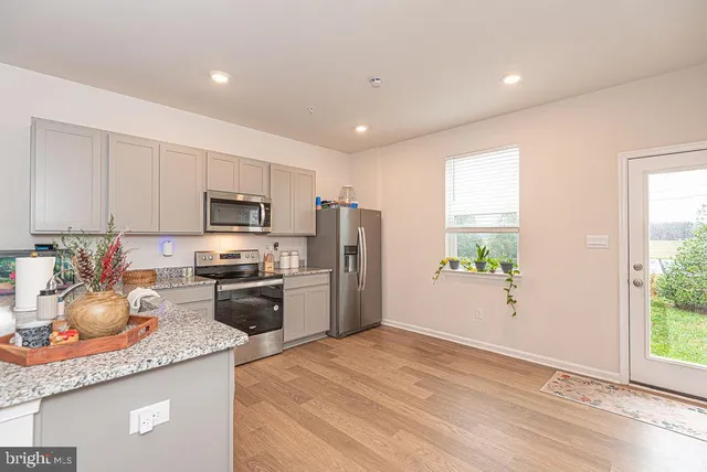 a kitchen with granite countertop a refrigerator oven a sink a window and stainless steel appliances