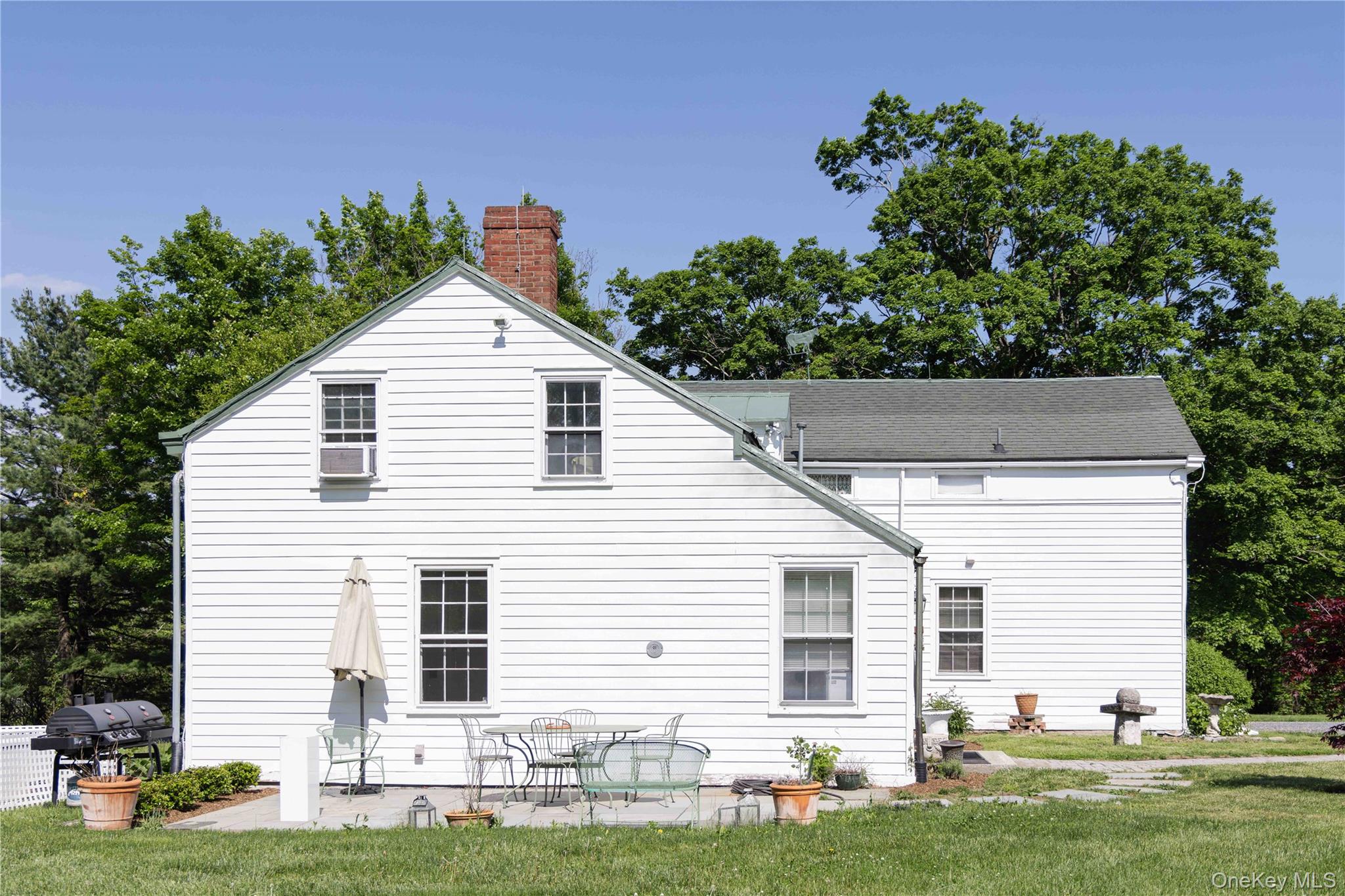 210 Middle Road Hudson, NY 12534 - Photo 6 of 42 White clapboard siding exterior with a brick chimney, gabled roofline, and multiple window openings