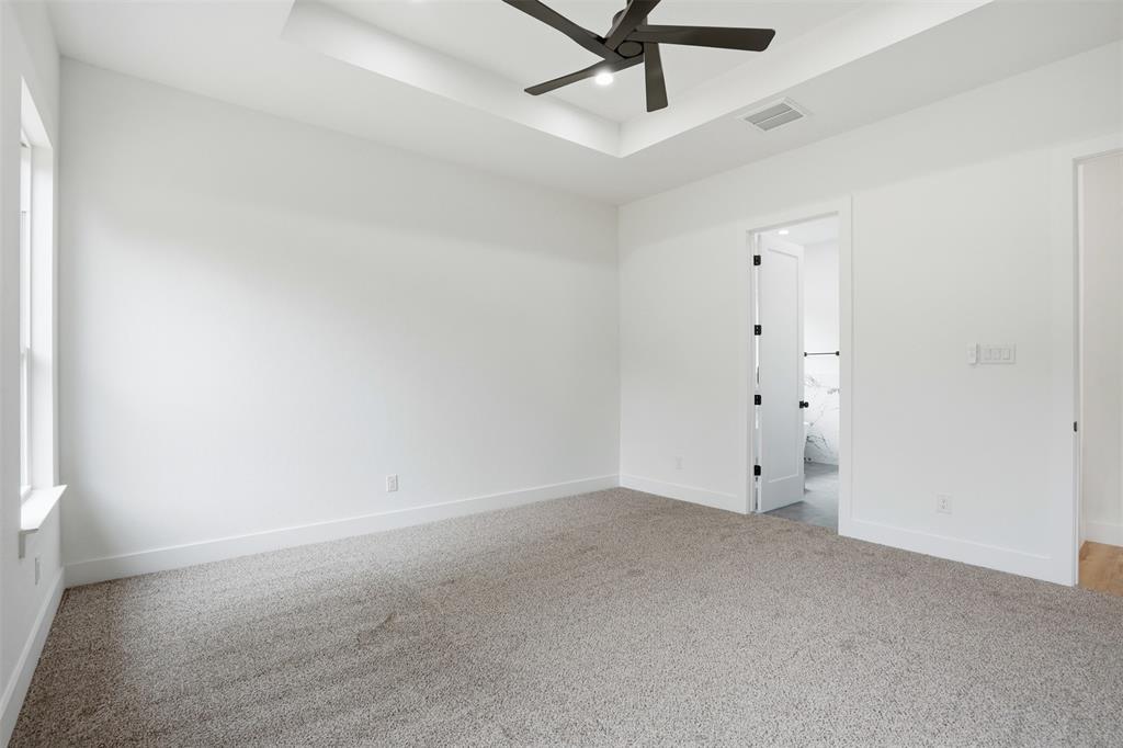 1111 Riverwood Road Dallas, TX 75217 - Photo 33 of 40 Spacious room featuring neutral carpeting, white walls, a tray ceiling with a ceiling fan, and a window with white trim