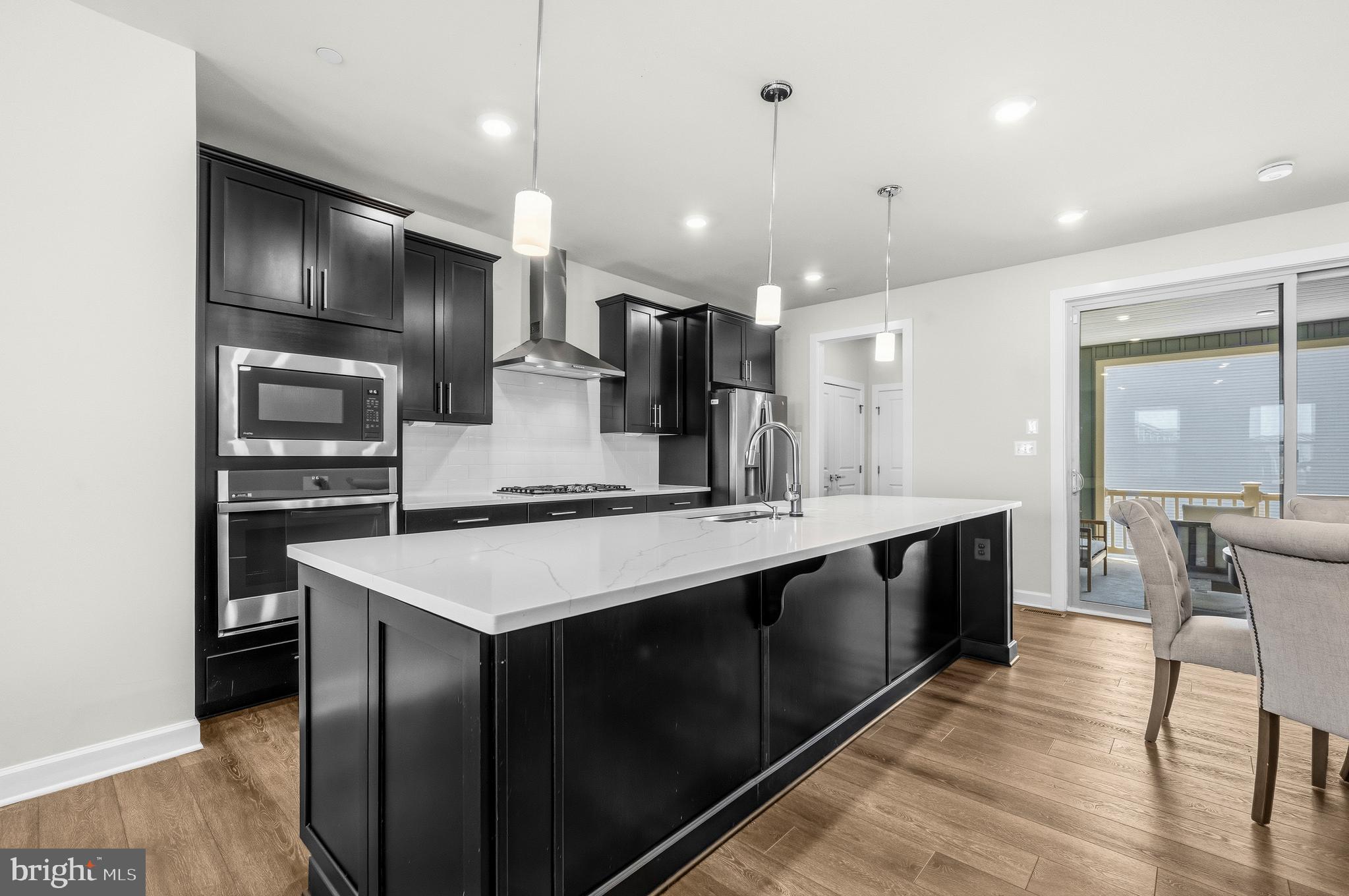 103 Brown Branch Road Laurel, MD 20708 - Photo 6 of 35 a large kitchen with a center island wooden floor stainless steel appliances and windows