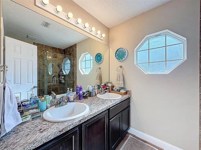 a bathroom with a granite countertop sink a large mirror and a shower